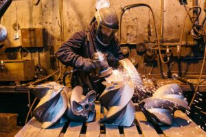 A foundry worker grinds the surface of a cast metal component at Taylor & Fenn.