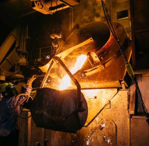 Molten metal pouring from furnace into a commercial sand mold.