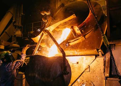 Molten metal pouring from furnace into a commercial sand mold.