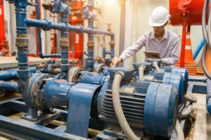 engineer inspecting blue and red cast components in a capital equipment system